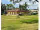 Exterior view of community building with a red tile roof, lush lawn, and mature trees at 4920 Locust Ne St # 116, St Petersburg, FL 33703
