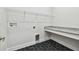 Laundry room featuring black hexagon tile flooring, upper shelves, and white cabinets at 5289 Everlong Dr, Apollo Beach, FL 33572