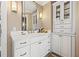 Bathroom vanity with white cabinetry, marble countertop, wall sconces, large mirror and cabinet for towel storage at 1124 Seville Ne Ln, St Petersburg, FL 33704