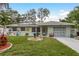 Charming single-story home featuring a well-manicured lawn, solar panels, and colorful landscaping at 1611 San Charles Dr, Dunedin, FL 34698
