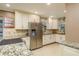 Well-lit kitchen featuring granite countertops, stainless steel refrigerator, and ample storage space at 1611 San Charles Dr, Dunedin, FL 34698