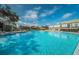 A large swimming pool with lounge chairs and umbrellas near a clubhouse on a sunny day at 2258 World Parkway W Blvd # 8, Clearwater, FL 33763