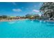 A large community pool with lounge chairs and colorful umbrellas on a sunny day at 2258 World Parkway W Blvd # 8, Clearwater, FL 33763