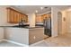 Kitchen with wood cabinets, black countertops, stainless steel refrigerator, and tile flooring at 12610 Geneva Glade Dr, Riverview, FL 33578