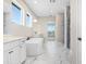 Modern bathroom with marble floors, white vanities, soaking tub, and a glass enclosed shower at 5211 Lake Venice Dr, Wimauma, FL 33598