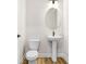Powder room features an oval mirror, pedestal sink, and wood look floors at 5211 Lake Venice Dr, Wimauma, FL 33598