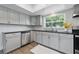 Kitchen includes stainless steel appliances, gray cabinets, granite countertop and wood-look floors at 1415 Ridge Ave, Clearwater, FL 33755