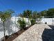 Fenced backyard with stone flooring, tropical landscaping, and furniture at 410 W Lemon St, Tarpon Springs, FL 34689