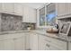 Bright kitchen area with white cabinets, granite counters, and a charming window view at 16403 Zurraquin De Avila, Tampa, FL 33613