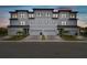 Modern three-story townhome exterior featuring a metal roof, three-car garage, lush landscaping, and impeccable curb appeal at 3027 Bermuda Sloop Cir, Ruskin, FL 33570