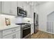 A modern kitchen features white cabinets, stainless steel appliances, quartz countertops, and wood-look tile flooring at 3027 Bermuda Sloop Cir, Ruskin, FL 33570