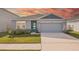 Charming single-story home featuring a light gray exterior, stone accents, a blue front door and a two-car garage at 31814 Oyster Trellis Ln, Wesley Chapel, FL 33545