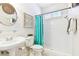 Stylish bathroom featuring pedestal sink, walk-in shower with turquoise curtain, and decorative macrame wall art at 15005 Lake Emerald Blvd, Tampa, FL 33618