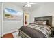 Comfortable bedroom with a beach scene TV, ceiling fan, and a gray, brown, and black patterned quilt at 15005 Lake Emerald Blvd, Tampa, FL 33618