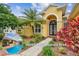 Inviting yellow home featuring a black double door entrance, lush landscaping, and a pool view on the side at 15005 Lake Emerald Blvd, Tampa, FL 33618