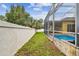 Grassy side yard leading to a screened-in pool enclosure, providing space and privacy at 15005 Lake Emerald Blvd, Tampa, FL 33618