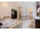 A luxurious bathroom with a jacuzzi tub, travertine tile, walk-in shower, and access to a walk-in closet at 310 8Th N Ave, St Petersburg, FL 33701