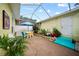 Enclosed patio featuring brick pavers, a dining set, lush landscaping, and access to the outdoors at 458 Grant St, Dunedin, FL 34698