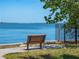 Waterfront park bench offers scenic views with trees, a fence, and open skies at 458 Grant St, Dunedin, FL 34698