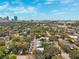 An aerial view of a tree-lined neighborhood shows houses and city buildings on the horizon under a beautiful, cloudy sky at 832 13Th N Ave, St Petersburg, FL 33701
