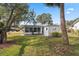 Backyard featuring well-maintained lawn, mature trees, and sunroom at 13000 Club Dr, Hudson, FL 34667