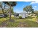 Well-maintained backyard featuring a lush lawn, mature trees, and a charming white home exterior at 13000 Club Dr, Hudson, FL 34667