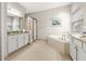 Bright bathroom featuring a soaking tub with tile surround, walk-in shower, and granite countertops at 30715 Tumbleberry St, Wesley Chapel, FL 33543