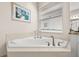 Close up of soaking tub with tile surround in bathroom featuring granite countertops and a window with blinds at 30715 Tumbleberry St, Wesley Chapel, FL 33543