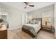 Bedroom with wood look flooring, ceiling fan, bedside lamps and ensuite bathroom at 30715 Tumbleberry St, Wesley Chapel, FL 33543