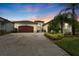 Beautiful home with a brick driveway, well-manicured landscaping, and a tile roof at sunset at 30715 Tumbleberry St, Wesley Chapel, FL 33543