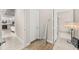 Hallway with tile and wood flooring leading to the kitchen and bathroom entrance with an eclectic floor lamp and mirror at 30715 Tumbleberry St, Wesley Chapel, FL 33543