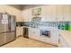 Well-equipped kitchen showcases stainless steel appliances, white cabinets, and a backsplash with blue mosaic tiles at 30715 Tumbleberry St, Wesley Chapel, FL 33543