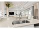 Bright kitchen boasts stainless steel sink, stone countertop and view to the living area at 30715 Tumbleberry St, Wesley Chapel, FL 33543