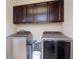 Modern laundry room featuring new front load washer and dryer and dark wood cabinets at 11125 Winthrop Lake Dr, Riverview, FL 33578
