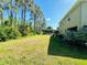 Expansive backyard featuring lush green grass, mature trees, and a screened-in pool area at 12127 Luftburrow Ln, Hudson, FL 34669