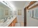 Bathroom with double sinks, wooden cabinets, tile flooring, and decorative seashell accents at 12127 Luftburrow Ln, Hudson, FL 34669