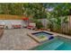 Backyard hot tub and seating area with brick pavers and tropical landscaping, perfect for outdoor relaxation at 4845 W Sunset Blvd, Tampa, FL 33629