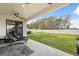 A covered patio, with fan, overlooks a fenced-in backyard with plush grass and tropical views at 14786 Horse Trot Rd, Lithia, FL 33547