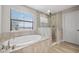 Bright bathroom with a standalone tub, glass shower and a large window overlooking the neighborhood at 14786 Horse Trot Rd, Lithia, FL 33547