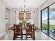 Dining room features wood table, chandelier and sliders to outside patio with green lawn at 14786 Horse Trot Rd, Lithia, FL 33547