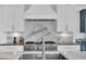 A modern kitchen features a range with a white range hood and marble backsplash, and black countertops at 200 Cordova Ne Blvd, St Petersburg, FL 33704