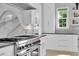 A modern kitchen features a range with a white range hood and marble backsplash, white cabinets and countertops at 200 Cordova Ne Blvd, St Petersburg, FL 33704