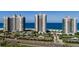 Aerial view of beachfront condo buildings, with pool, tennis courts, lush landscaping and road at 1520 Gulf Blvd # 1404, Clearwater Beach, FL 33767