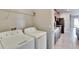 Functional laundry room equipped with a washer, dryer, overhead shelf, and a connecting hallway to the kitchen at 6834 Blue Moon Way, Sun City Center, FL 33573