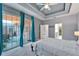 Bedroom features a queen bed, tray ceiling, and glass doors to a screened-in porch with dining and seating area at 302 Latitude Pl, Apollo Beach, FL 33572