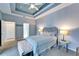 Bedroom features a tray ceiling, ceiling fan, queen bed, with accent furniture and two entry ways at 302 Latitude Pl, Apollo Beach, FL 33572