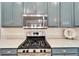 Kitchen with stainless steel appliances, blue cabinets, and white tile backsplash at 302 Latitude Pl, Apollo Beach, FL 33572