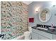 Charming half-bathroom with vibrant floral wallpaper, a sleek vanity, and an oval mirror at 5608 Rockfield Loop, Valrico, FL 33596