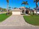 Beautiful single-story home features manicured lawn, lush landscaping, and a brick-paved driveway at 924 Landmark S Cir, Tierra Verde, FL 33715