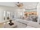 Bright and airy living room with a large white sofa, view of the kitchen, and access to an outdoor sitting area at 924 Landmark S Cir, Tierra Verde, FL 33715